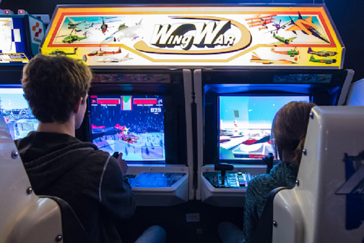 Two people playing Wing War arcade flight simulator game